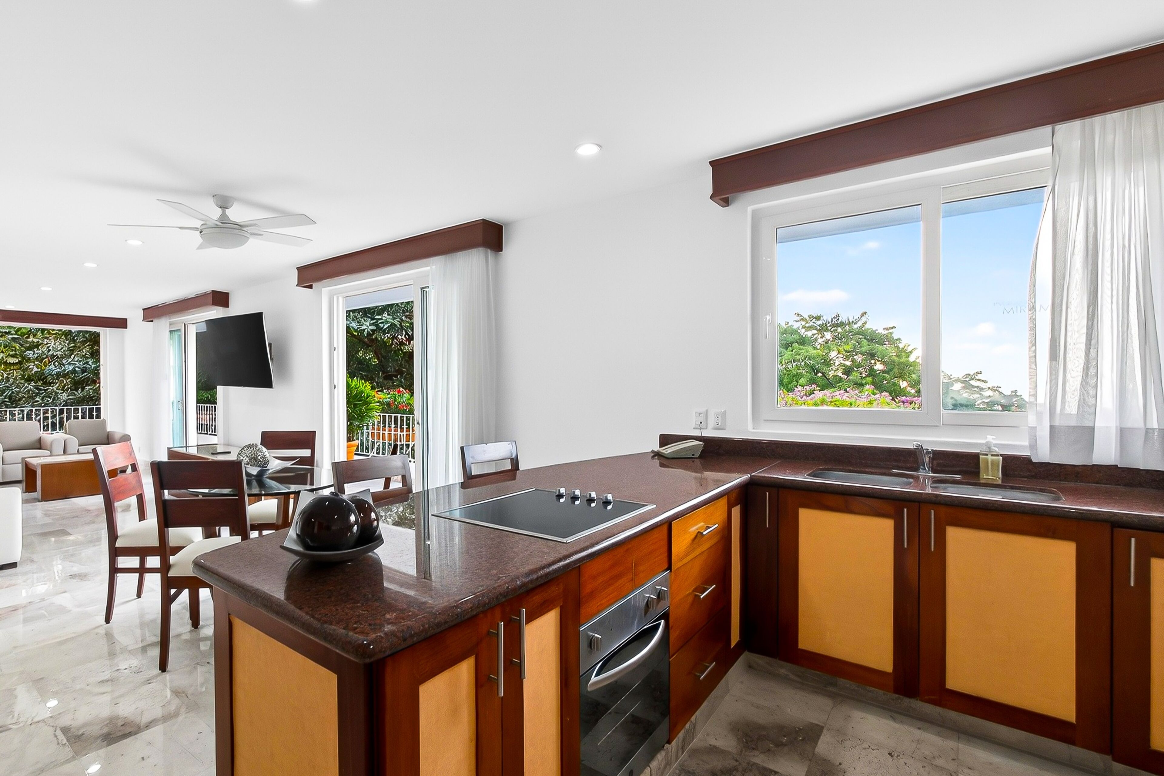 A modern kitchen with a large island, built-in oven, and a dining area with a TV.