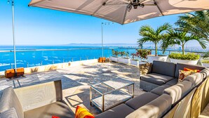 Eine Terrasse mit einer Couch, einem Couchtisch und einem großen Sonnenschirm.