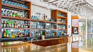 Eine Bar mit mehreren Regalen voller Spirituosenflaschen, einer polierten Granitabdeckung und einer modernen Leuchte.