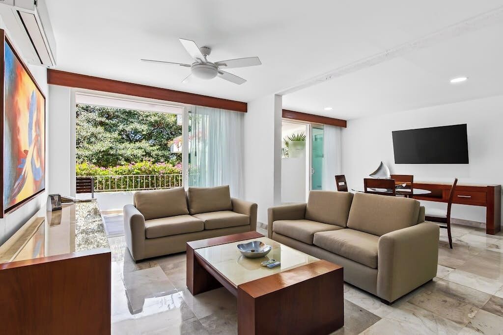 A modern living room with two sofas, a coffee table, a TV, and a ceiling fan.