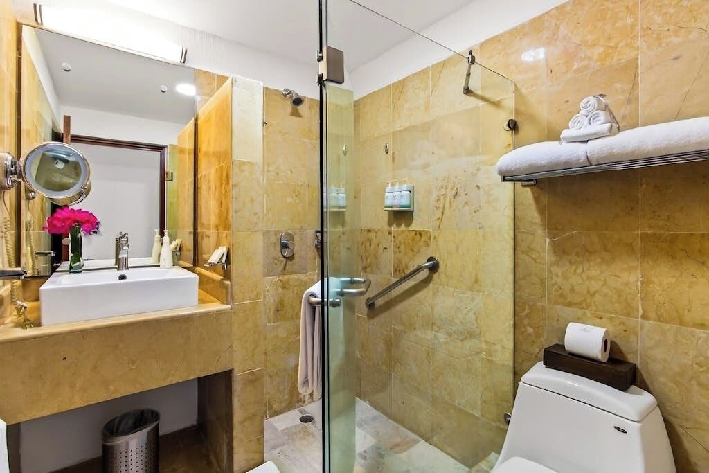 Un baño con ducha envuelta en vidrio, un lavabo con espejo y un inodoro.