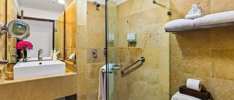 Un baño con ducha envuelta en vidrio, un lavabo con espejo y un inodoro.