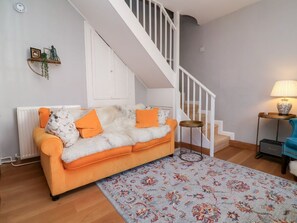 A living room with a sofa, a patterned rug, a staircase, a lamp, and a radiator.