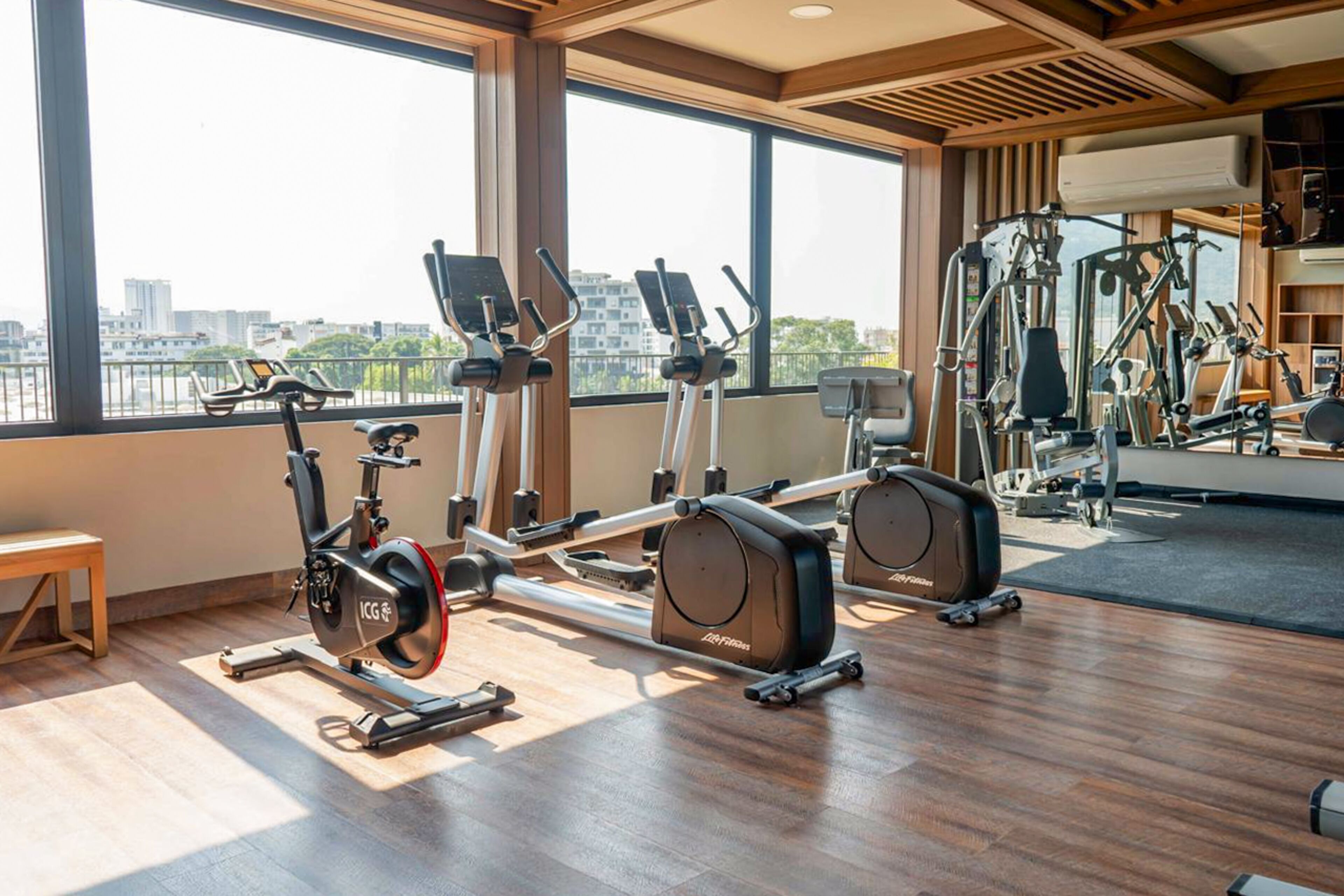 A gym with cardio machines, a rowing machine, and a bench.