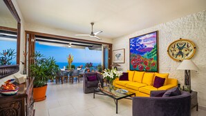 A living room with a yellow sofa, a gray armchair, a coffee table, and a view of the ocean. - Paraiso del Mar 1BR/1BA Ocean View in Puerto Vallarta (Puerto Vallarta)
