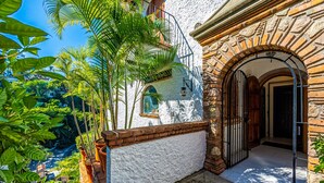 A building with a white stucco exterior, a brick archway, and a view of a river. - Paraiso del Mar 1BR/1BA Ocean View in Puerto Vallarta (Puerto Vallarta)