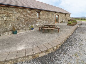 A stone building with a gravel driveway, a wooden bench, and potted plants. - The Stall, Llanmorlais (Swansea)