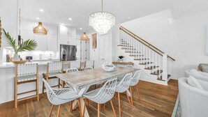 Eine moderne Küche mit weißen Schränken, einem Holzespeisetisch und einer Treppe.