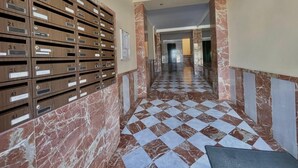 A hallway with a checkered floor, marble walls, and wooden mailboxes. - Terrasol Zeus in Torre del Mar (Velez-Malaga)