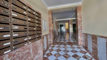 Un pasillo con piso de cuadros, paredes de mármol y buzones de madera.