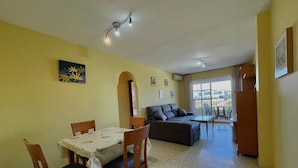 A dining area with a table and chairs, a sofa, and a balcony with a view. - Terrasol Zeus in Torre del Mar (Velez-Malaga)