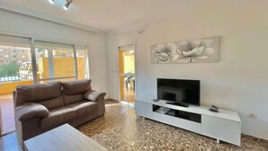 Een woonkamer met een bank, televisie en kunstwerk aan de muur.