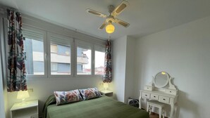 A bedroom with a bed, a dresser with a mirror, a ceiling fan, and a window with curtains. - Terrasol SAN Francisco Larios (Velez-Malaga)