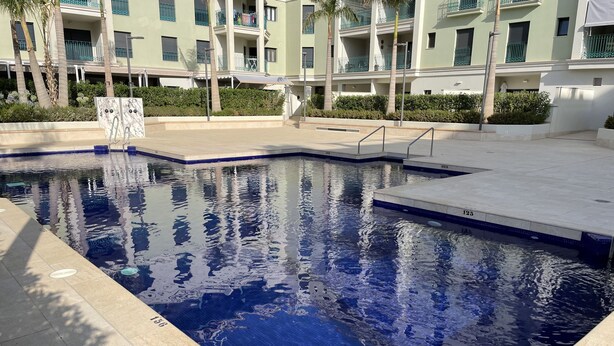 A swimming pool with clear water, surrounded by a tiled deck and a building with balconies. - Terrasol Azucarera 4 (Velez-Malaga)