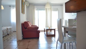 A living room with a sofa, a dining table with chairs, a hanging light fixture, and a window with curtains. - Terrasol Palma in Torre del Mar (Velez-Malaga)