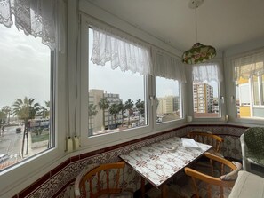 Ein Zimmer mit Erkerfenster, Tisch, Stühlen und Blick auf die Stadt.