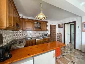 Eine Küche mit Holzausstattung, einer Granit Arbeitsplatte, einer Mikrowelle und einer Kaffeemaschine.