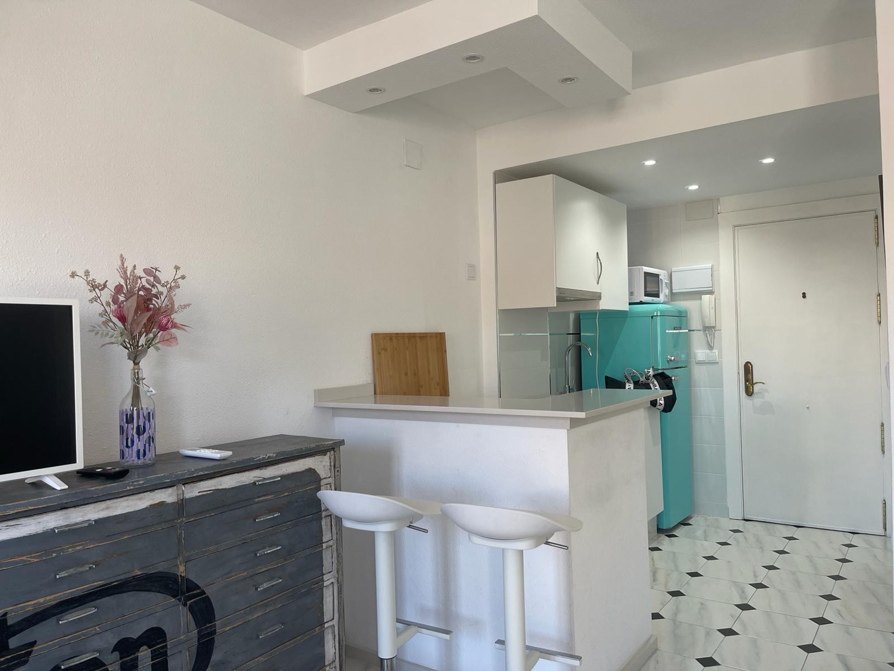 A modern kitchen with a bar area, a television, and a decorative vase.
