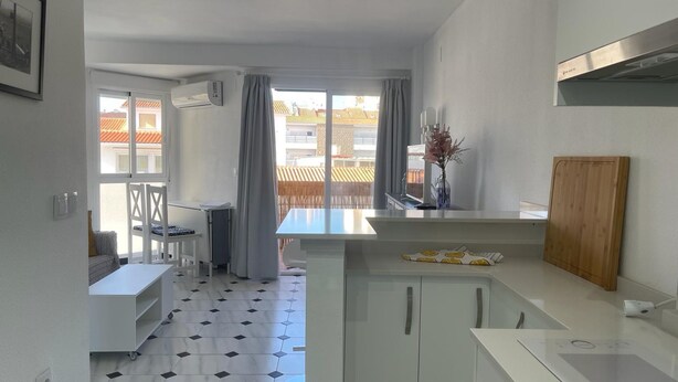 A modern kitchen with a dining area, a view of the outside, and a balcony. - Terrasol Plazamar 6-2 (Velez-Malaga)