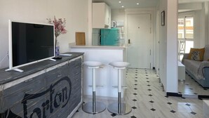 A modern kitchen with a teal refrigerator, a white countertop, and a bar area with stools. - Terrasol Plazamar 6-2 (Velez-Malaga)