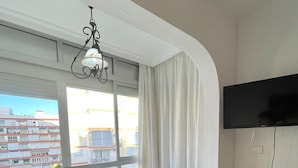 A modern apartment with a dining area, a TV, and a balcony with a city view. - Terrasol California 4 (Velez-Malaga)