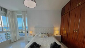 A hotel room with a bed, two bedside lamps, a large wooden wardrobe, and a view of the sea. - Terrasol California 4 (Velez-Malaga)