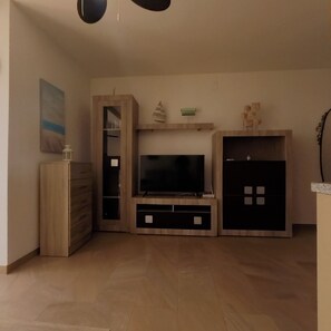 A living room with a flat-screen TV, wooden cabinets, and a painting on the wall. - Terrasol Plazamar Estudio 2-6 (Velez-Malaga)