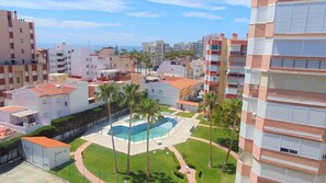 A residential area with a swimming pool surrounded by palm trees and a clear view of the sea. - Terrasol Plazamar Estudio 2-6 (Velez-Malaga)