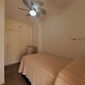 A bedroom with a bed, a ceiling fan, a wardrobe, and a nightstand. - Terrasol Plazamar Estudio 2-6 (Velez-Malaga)
