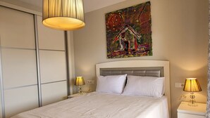Un dormitorio con cama, lámparas de noche, un cuadro en la pared y un armario.