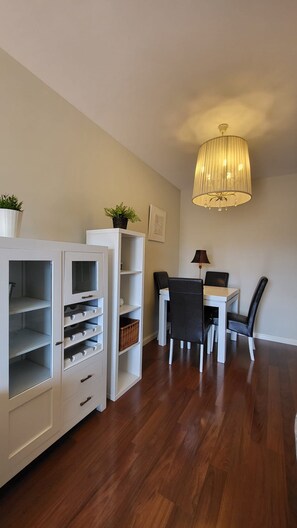 Ein Essbereich mit Tisch, Stühlen, einer Chandelierleuchtre und weißen Schränken mit offenen Regalen.