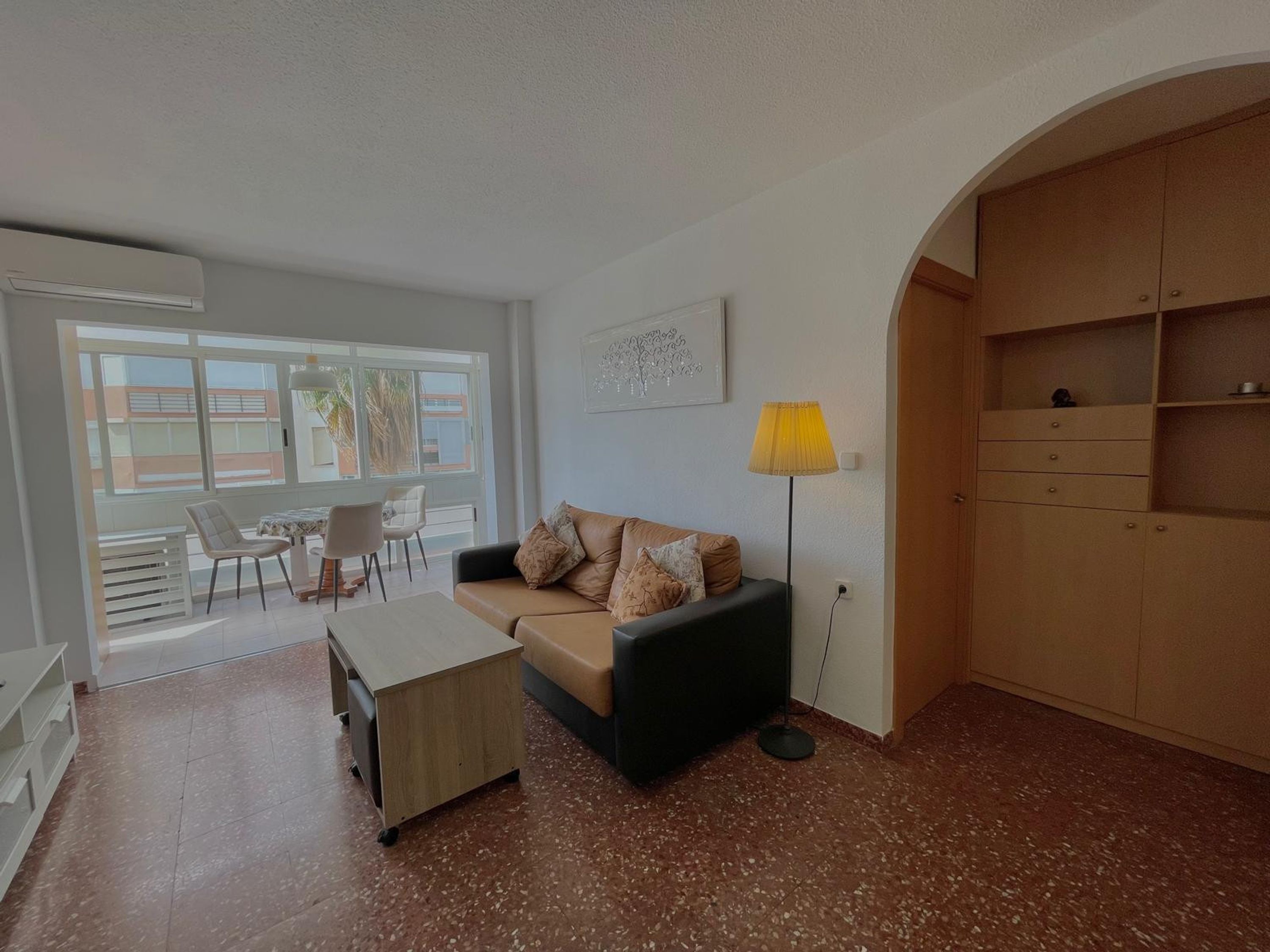 Ein Wohnzimmer mit einer Couch, einem Couchtisch, einer Lampe und Blick ins Freie.