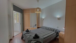 Ein Schlafzimmer mit Bett, Kleiderschrank, Nachttisch und einer Pendelleuchte.