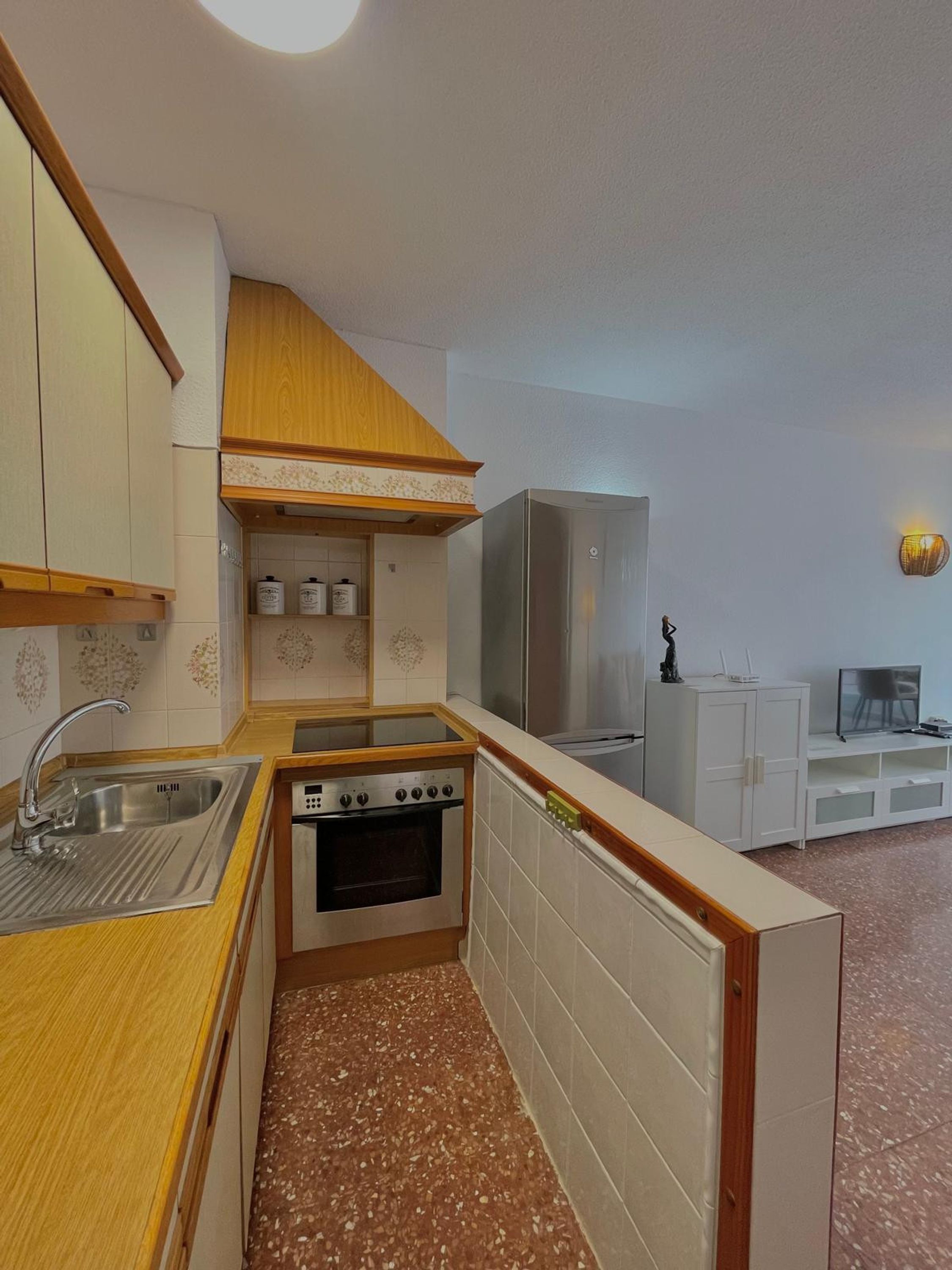 A compact kitchen with a stove, sink, and white cabinets.