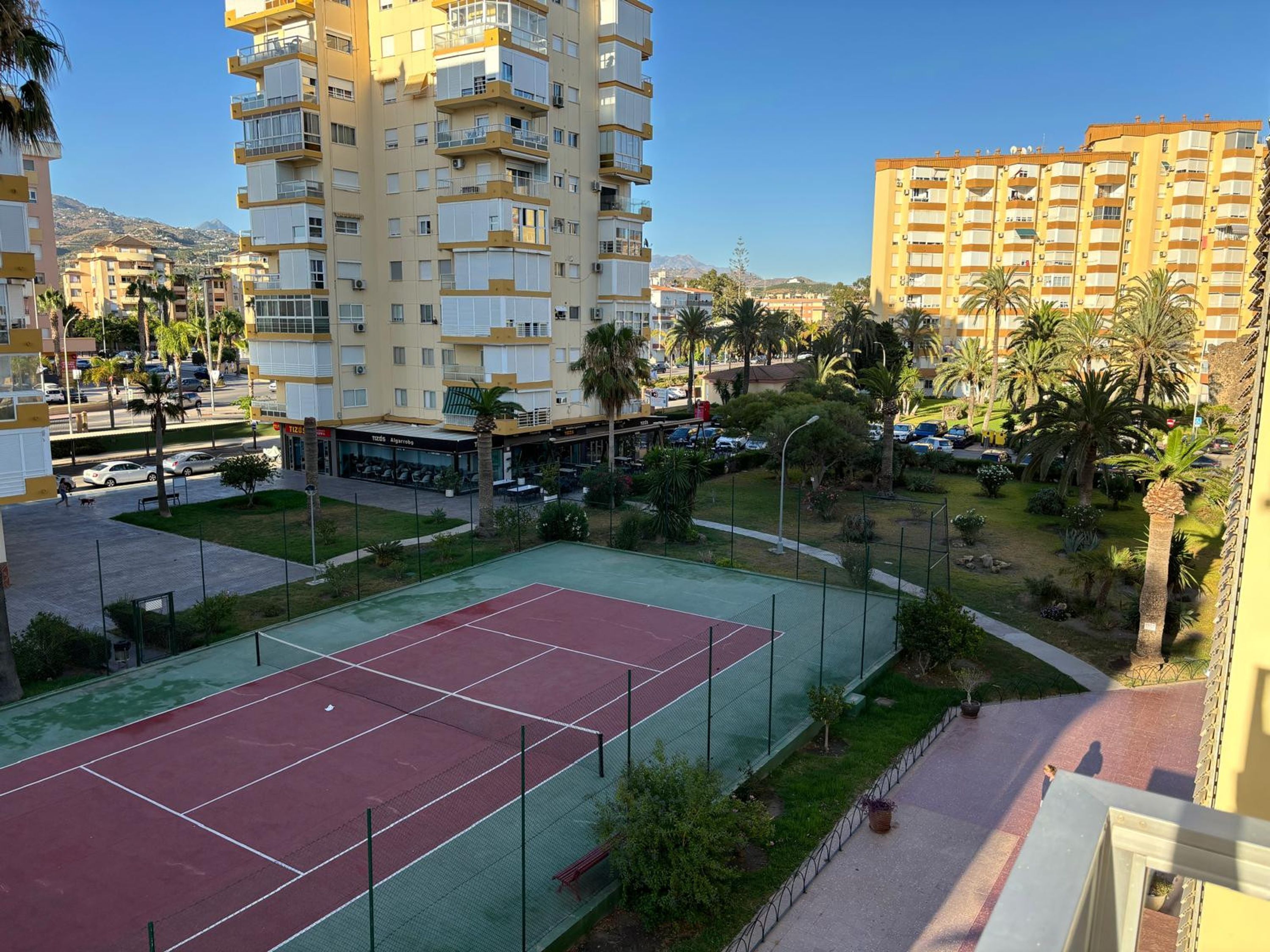 Zona residencial con cancha de tenis, edificios altos y cielo despejado.