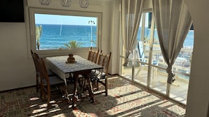 A dining area with a table and chairs, a view of the sea, and patterned floor tiles. - Terrasol Sobre EL MAR Habana 4 (Algarrobo)