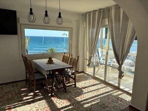 A dining area with a table and chairs, a view of the sea, and patterned floor tiles. - Terrasol Sobre EL MAR Habana 4 (Algarrobo)
