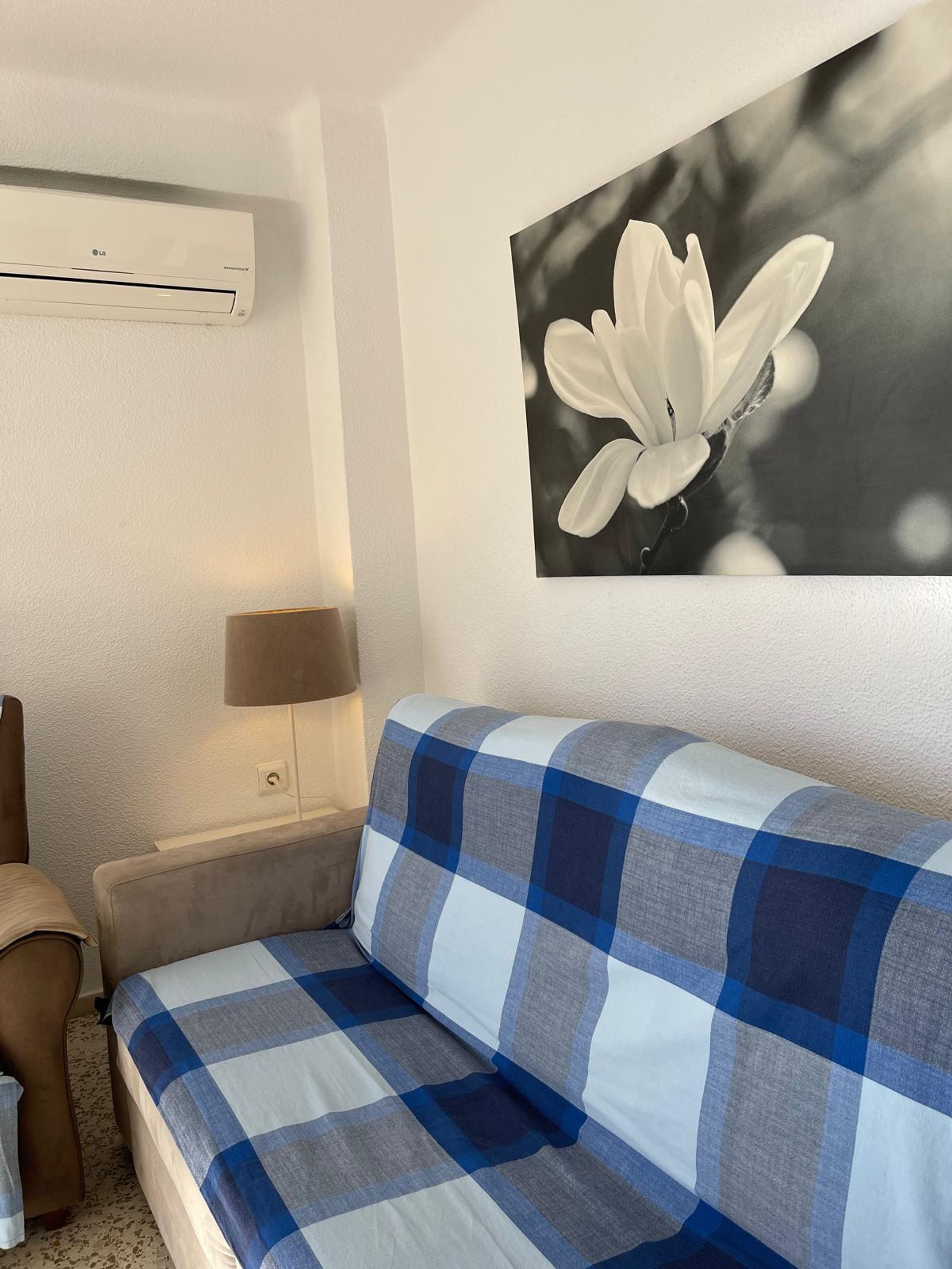 A modern room with a sofa, a lamp, and a wall-mounted air conditioner.