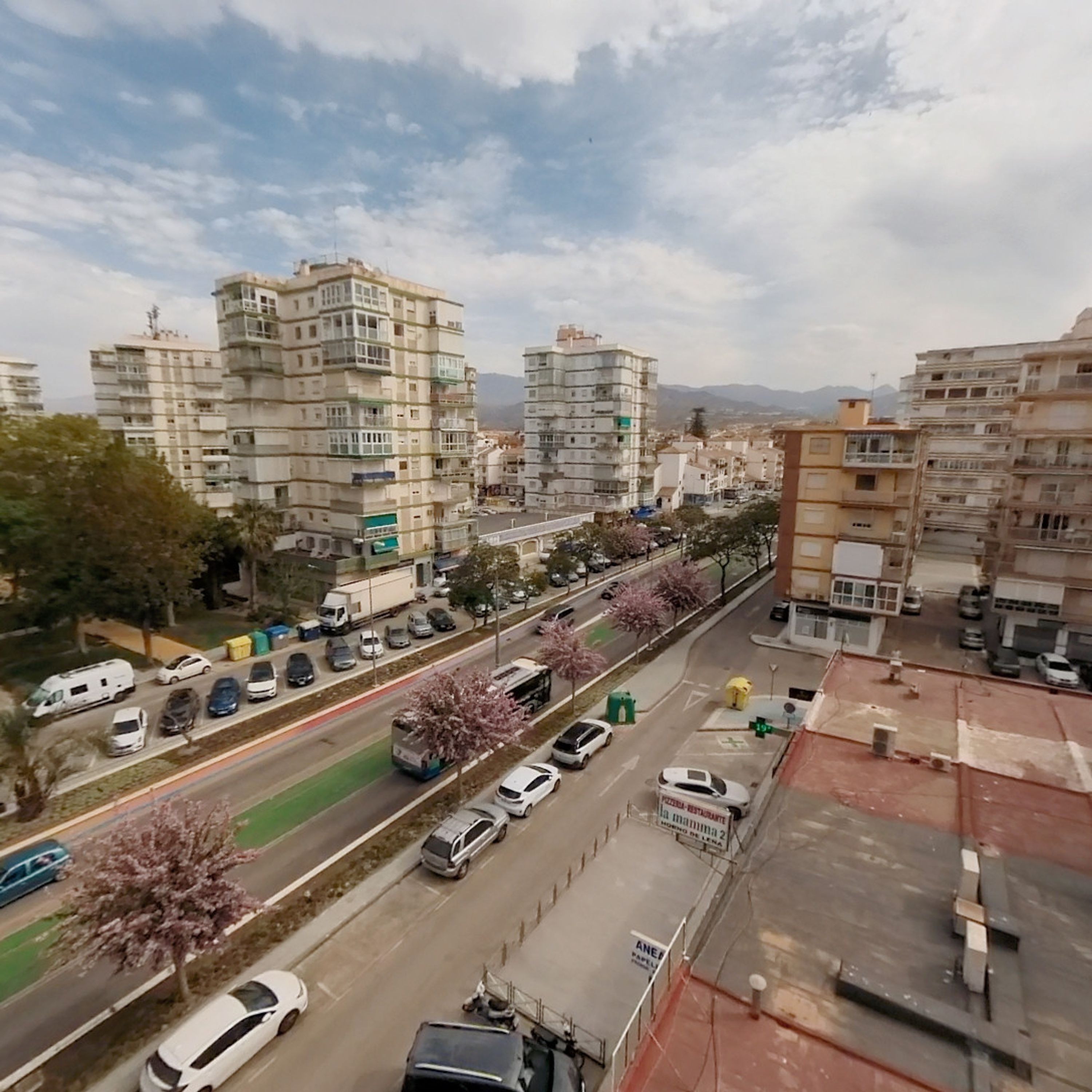 A multi-story urban street with vehicles, trees, and buildings.