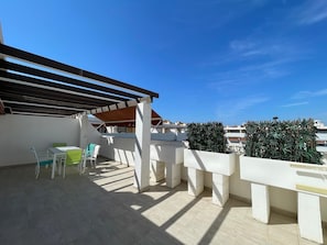 Eine Dachterrasse mit einer Pergola, Sitzgelegenheiten im Freien und Blick auf die Stadtlandschaft.