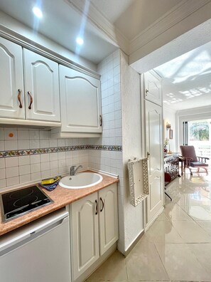 A modern kitchen with white cabinetry, a built-in oven, and a sink. - Terrasol Plazamar 3-6 (Velez-Malaga)