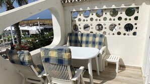 A patio with white furniture, a round table, and a wall with circular mirrors. - Terrasol Trai AS A1- 1 Linea Playa (Velez-Malaga)