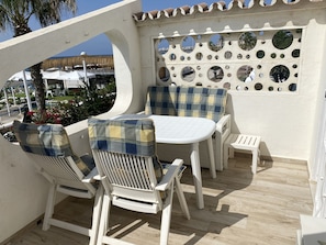 Eine Terrasse mit weißer Möbel, einem runden Tisch und einer Wand mit runden Spiegeln.