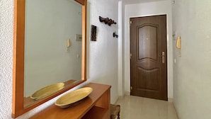A hallway with a wooden vanity, a large mirror, and a door at the end. - Terrasol Caracola 3 in Torre del Mar (Velez-Malaga)