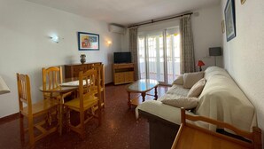 Un soggiorno con un divano, sedie in legno, una televisione e un tavolo da pranzo.