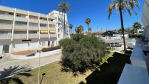 Un edificio a più piani con balconi, palme e un cielo azzurro limpido.