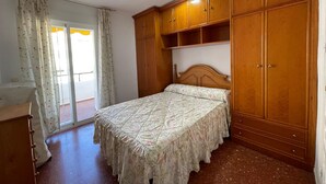 Una camera da letto con un letto, un armadio in legno e una porta scorrevole in vetro che dà sull'esterno.