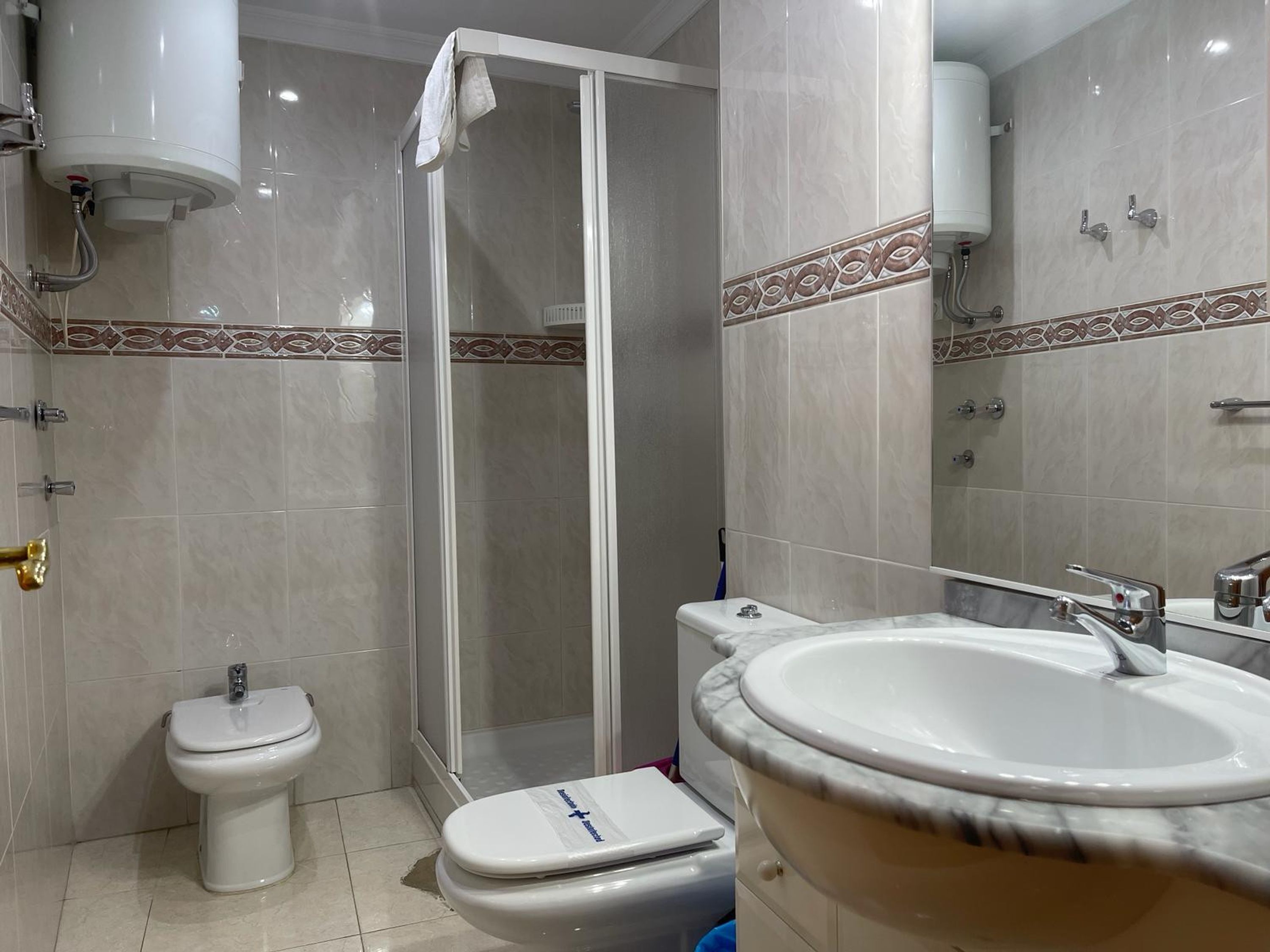A bathroom with a toilet, bidet, shower, and sink.