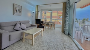 A living room with a sofa, coffee table, and dining area with chairs and a table. - Terrasol SAN Gerardo 2-2-2 Frontal AL MAR (Velez-Malaga)
