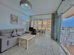 A living room with a sofa, coffee table, and dining area with chairs and a table. - Terrasol SAN Gerardo 2-2-2 Frontal AL MAR (Velez-Malaga)